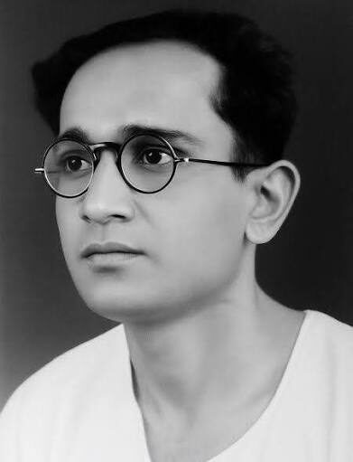 Studio portrait of a young Batukeshwar Dutt in round spectacles, looking to one side.