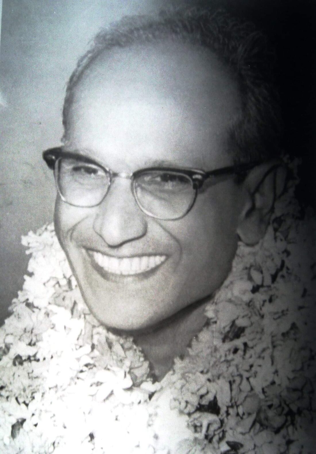Close portrait of Batukeshwar Dutt in later life, smiling, wearing spectacles and a flower garland.